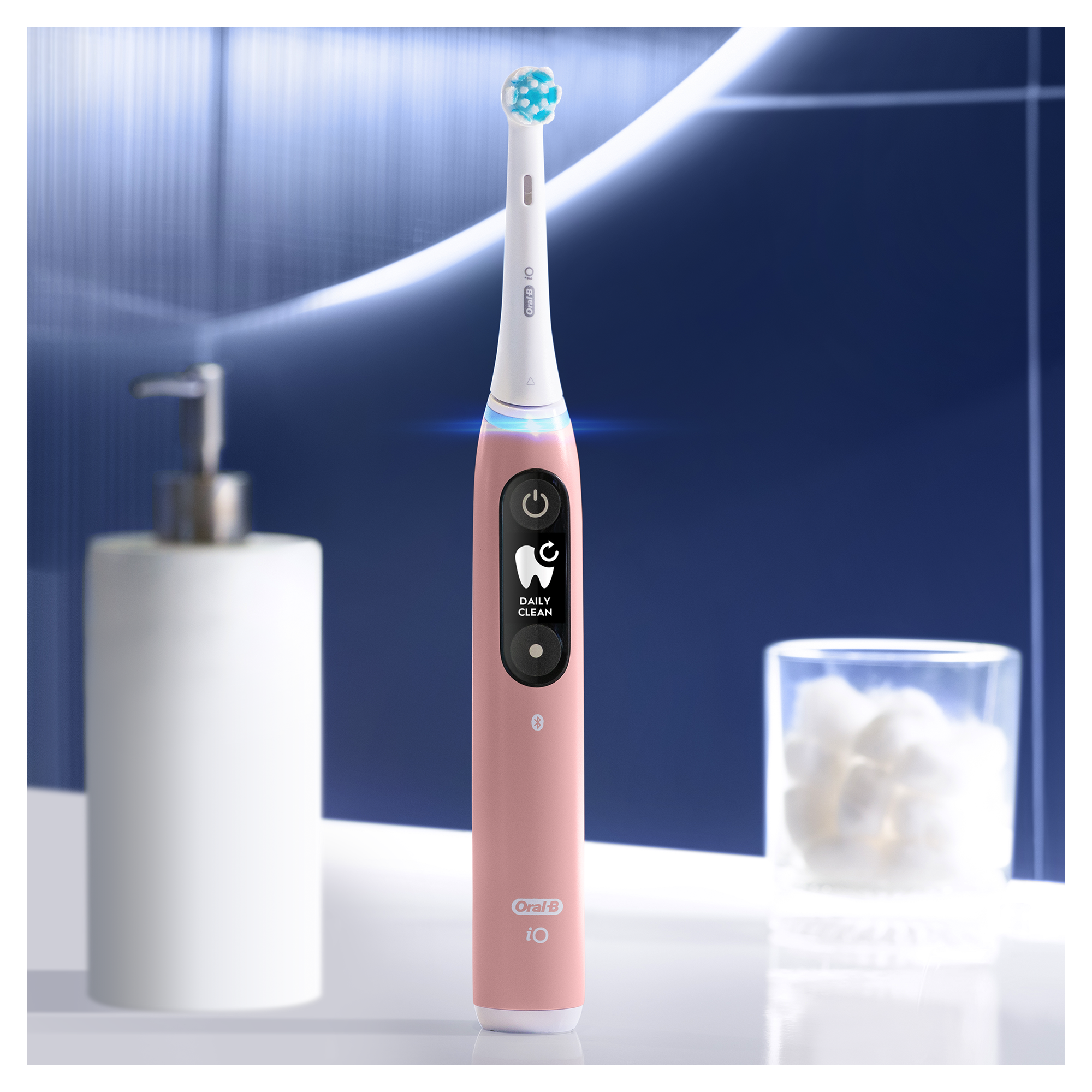 Brosse à dents électrique rose avec écran, verre et savon.