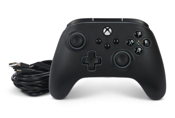 Ein schwarzer Xbox-Controller mit USB-Kabel auf einer weißen Oberfläche.