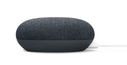 Mały, owalny, ciemnoszary głośnik Google Nest Mini z białym przewodem zasilającym. Stoi na białej powierzchni.