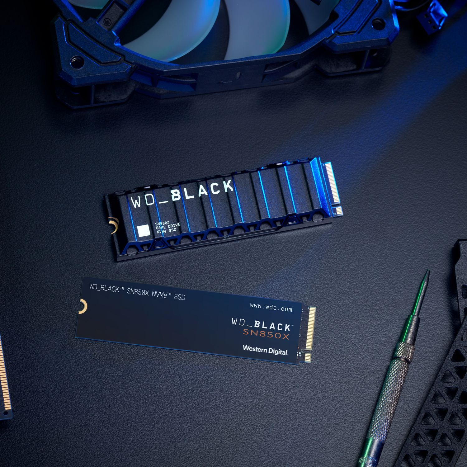 Twee WD_BLACK SN850X NVMe SSD's. Eén geïnstalleerd, één op de tafel. Gereedschap en koeler op de achtergrond.