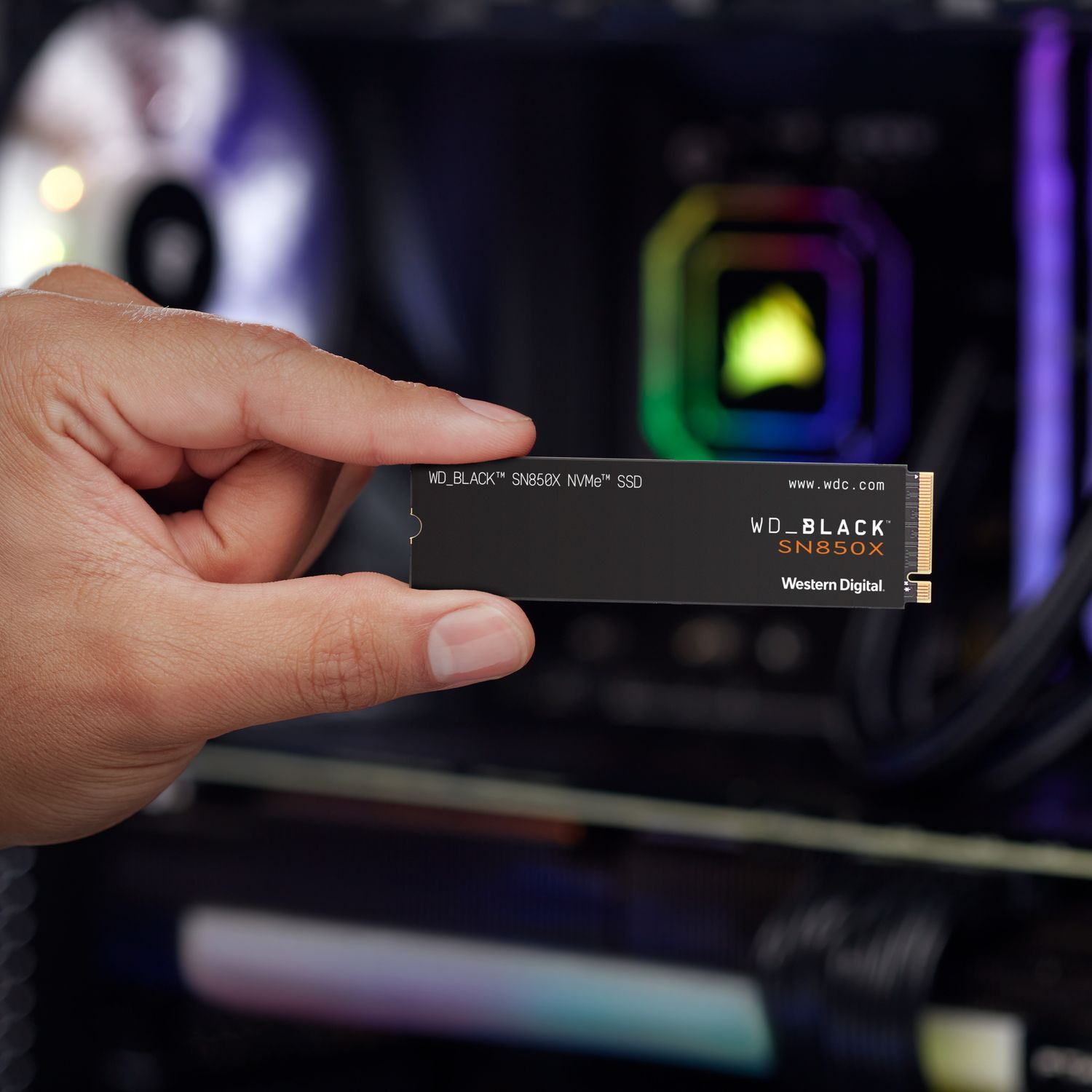 Hand die een zwarte SSD vasthoudt. De SSD heeft witte tekst.