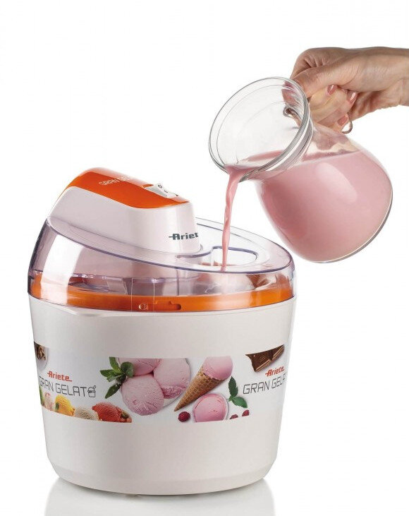 Maszyna do lodów jest napełniana różowym płynem ze szklanego dzbanka. Ma pomarańczową pokrywę.