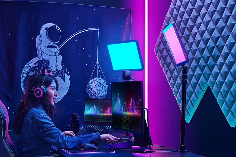 Kobieta gra w pokoju z kolorowymi światłami, monitorem i panelami wygłuszającymi.