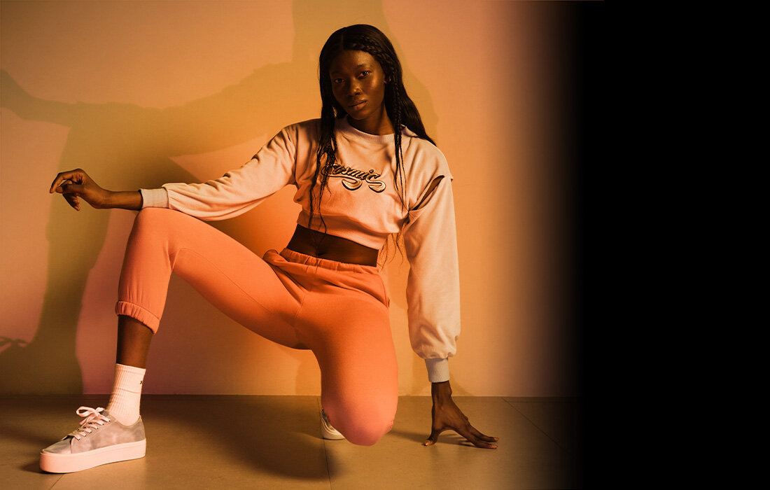 Kobieta w różowym stroju sportowym pozuje na czarnym tle.