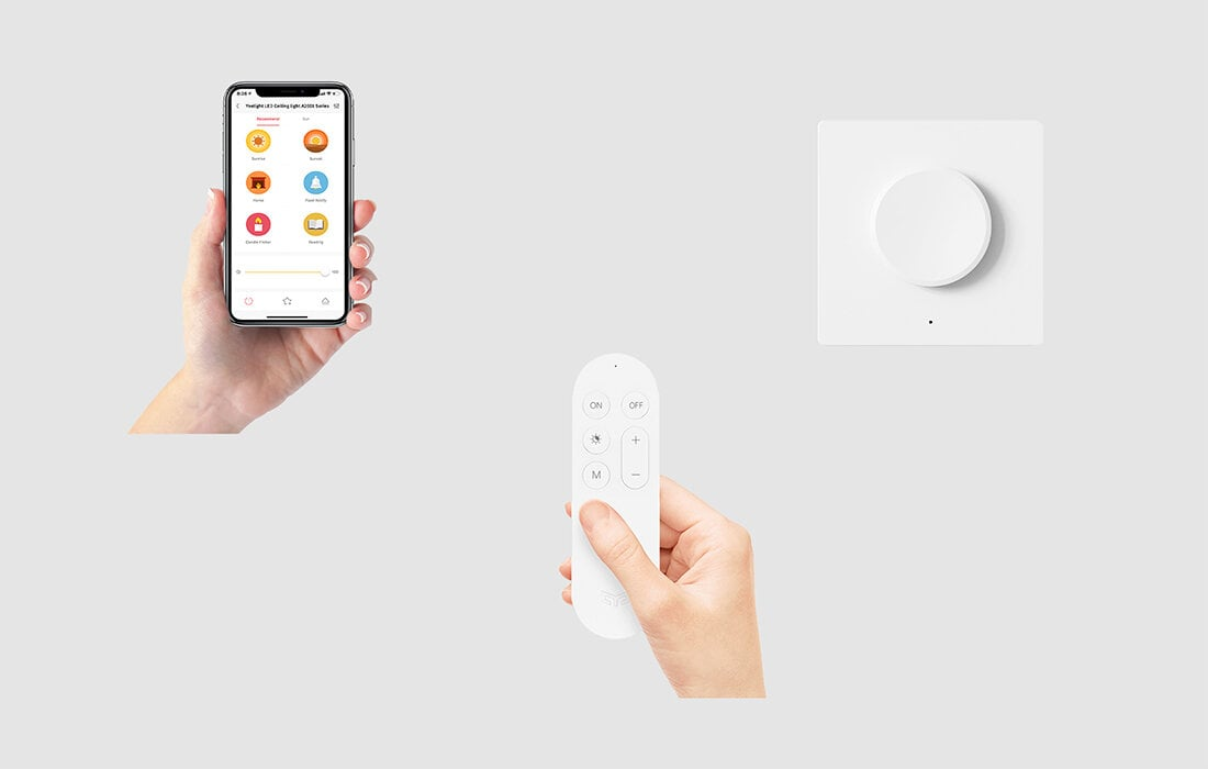 Ręka trzymająca telefon z aplikacją, ręka z pilotem. Biały przycisk smart home.