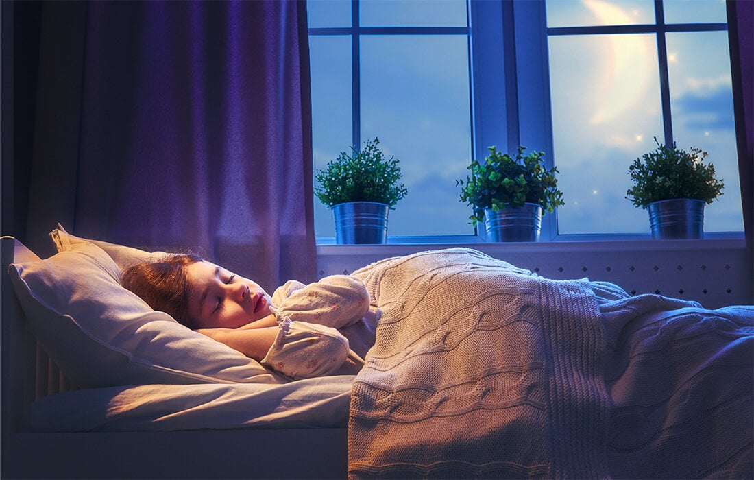 Dziewczynka śpiąca w łóżku w nocy. Okno z roślinami, widoczny księżyc.