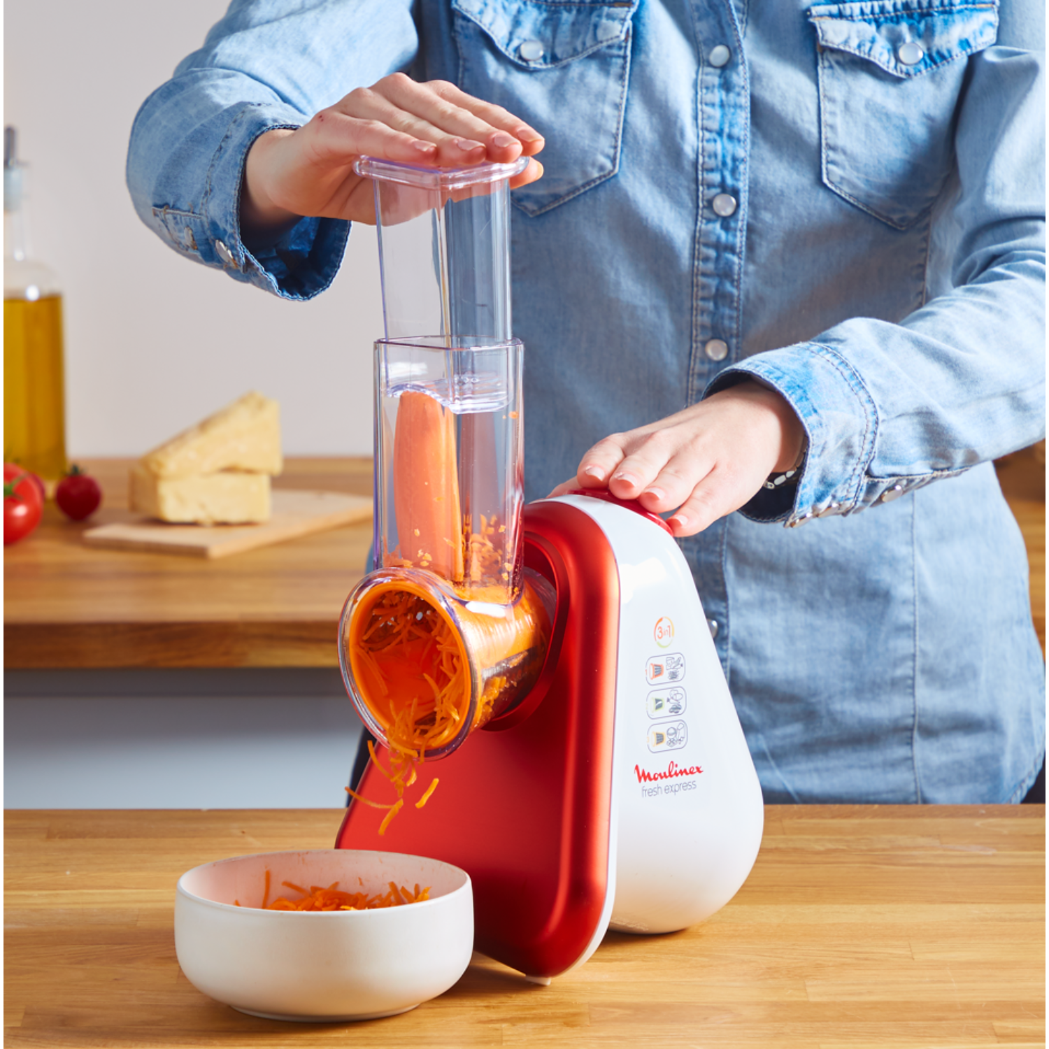 A person uses a red and white Moulinex Fresh Express food slicer.