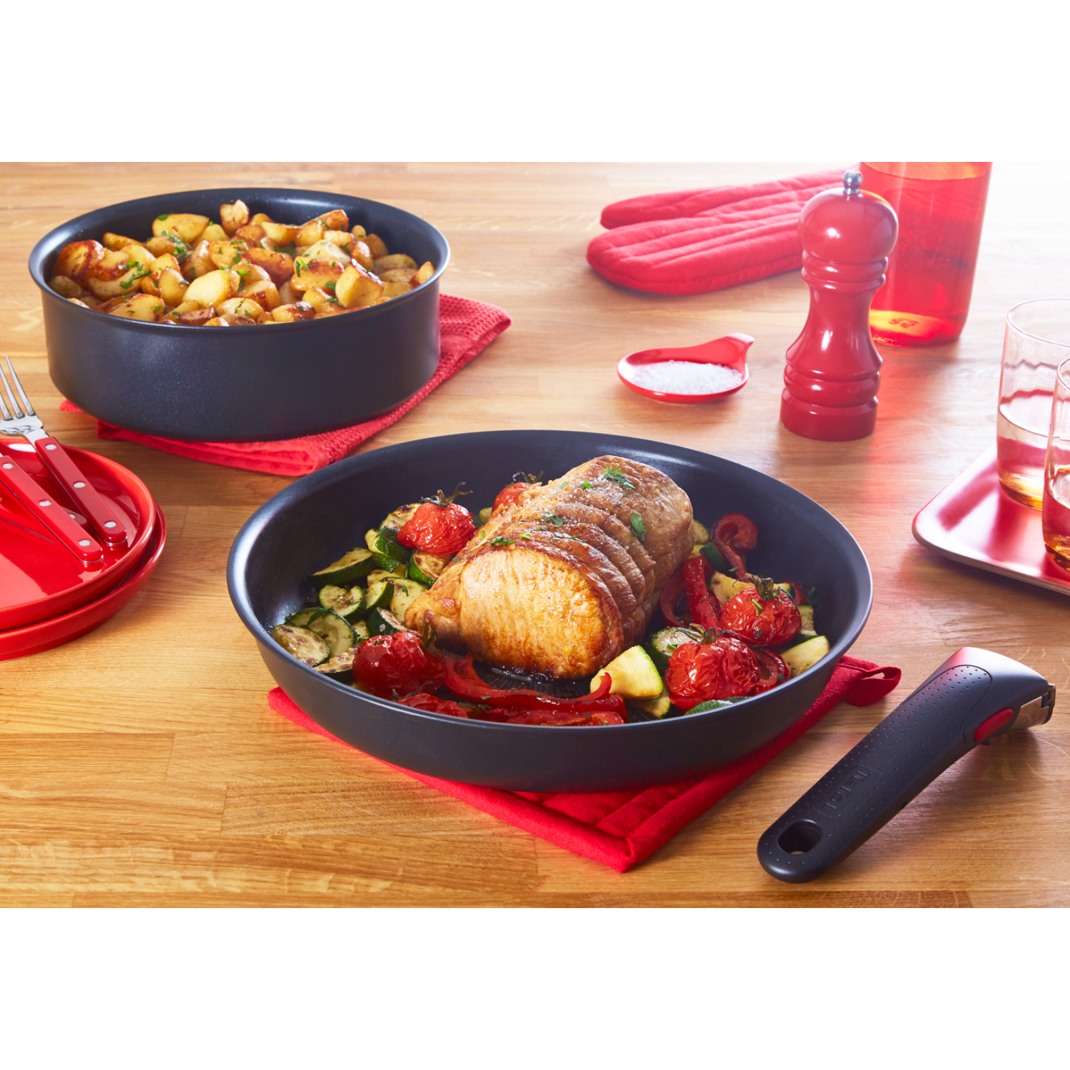 Une table avec de la nourriture. Une poêle avec de la viande et des légumes, avec d'autres plats et ustensiles.