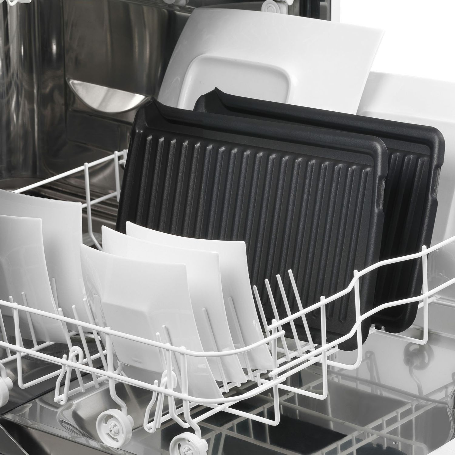 Dishwasher interior with white plates and black grill pans.
