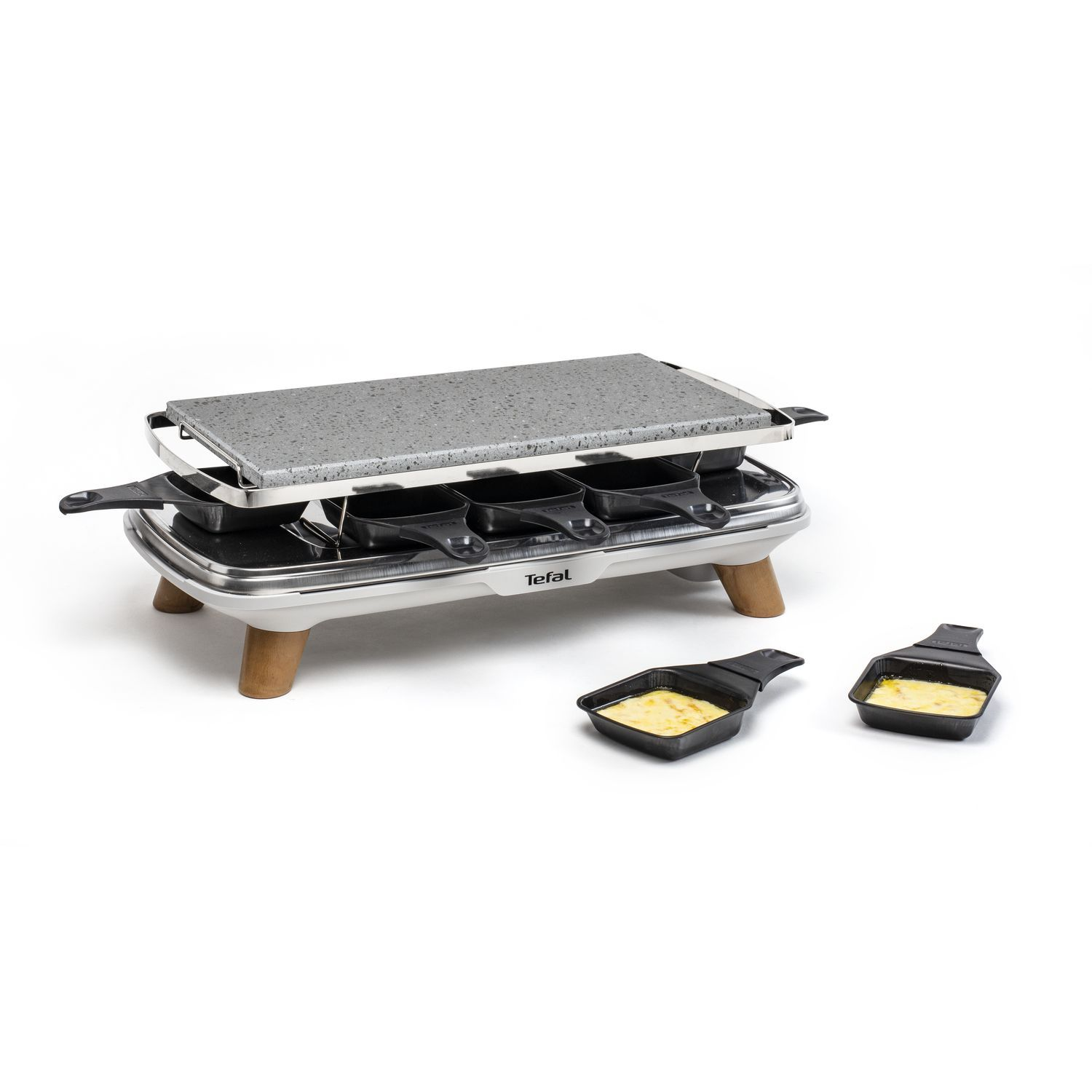 Een raclette grill met een stenen bovenkant, met vier individuele pannetjes en twee met kaas.