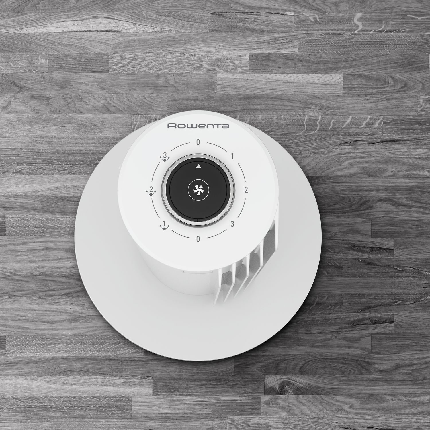 Bovenaanzicht van een witte ventilator met een zwarte bedieningsknop op een grijs houten oppervlak.