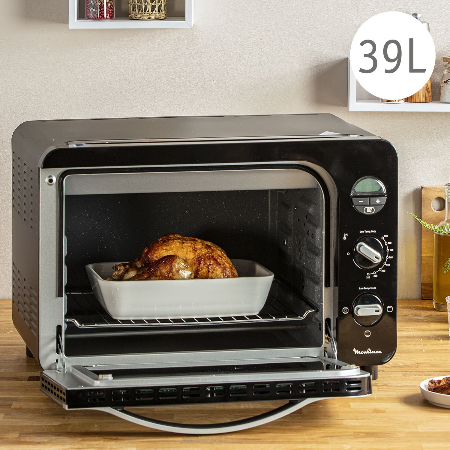 Zwarte Moulinex oven met gebraden kip erin. Ovendeur is open. Witte bakplaat.