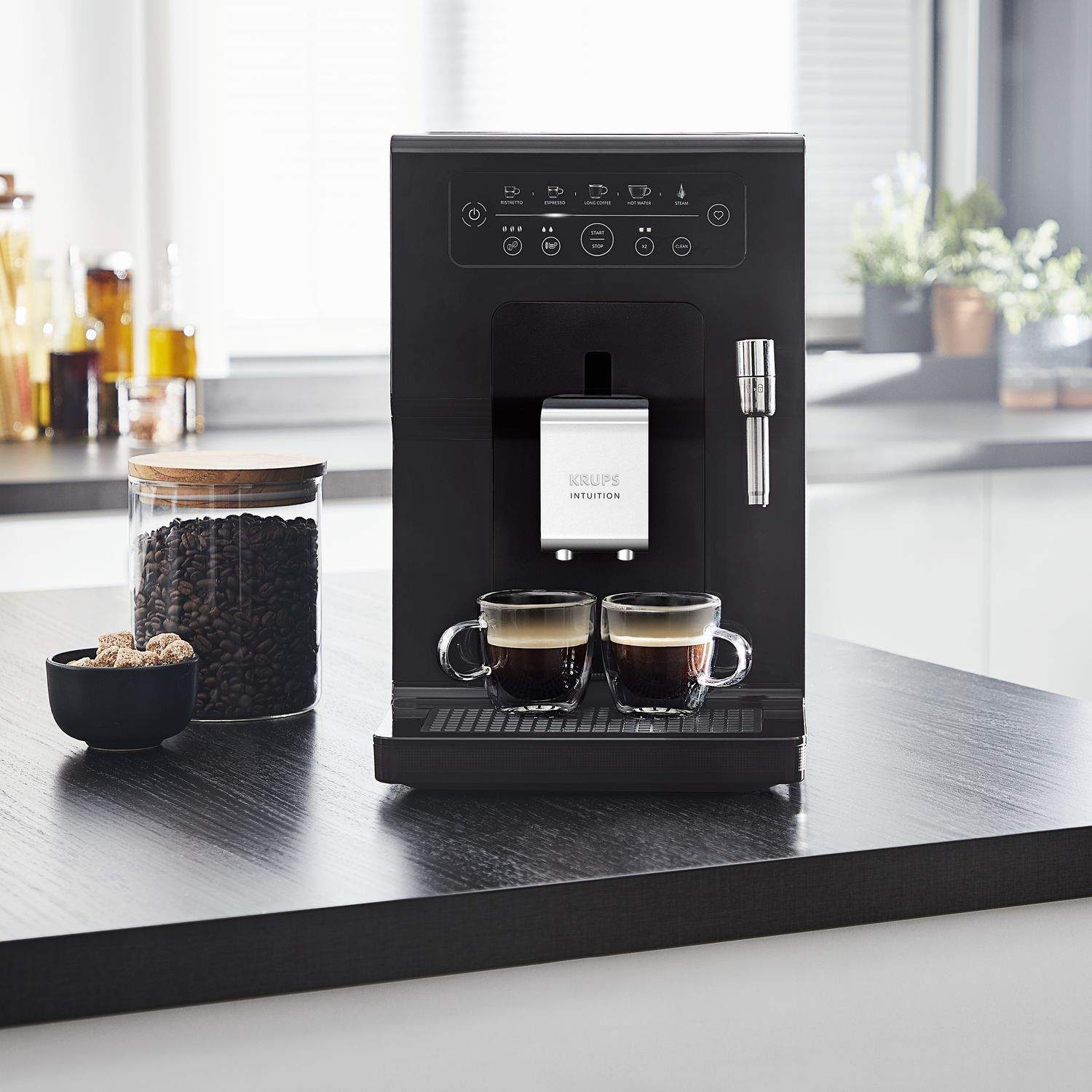 Zwarte Krups Intuition koffiemachine met twee kopjes koffie en koffiebonen.