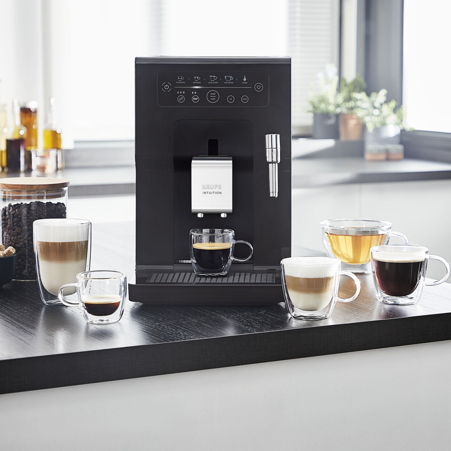 Zwarte Krups Intuition koffiemachine met koffiekopjes op een zwart aanrecht.
