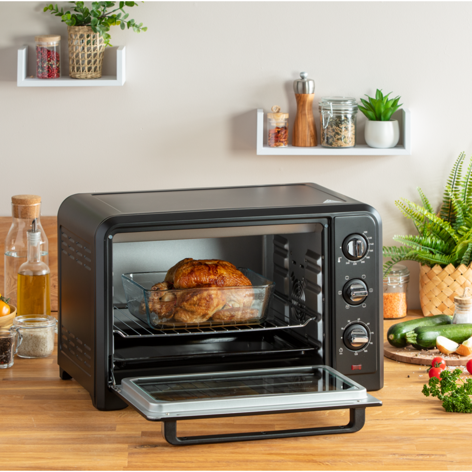 Zwarte oven met een gebraden kip erin, omgeven door keukenelementen.