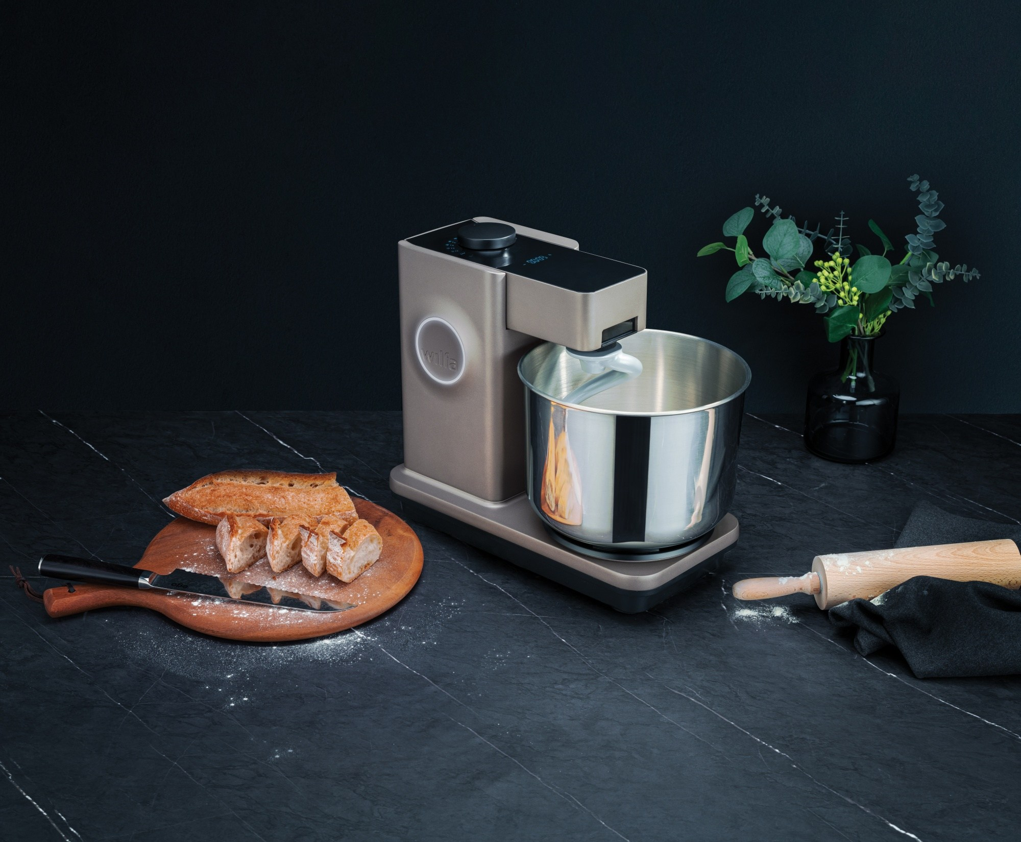 Un appareil de cuisine avec des articles de préparation des aliments. Pain, rouleau à pâtisserie et feuillage sur une surface noire.