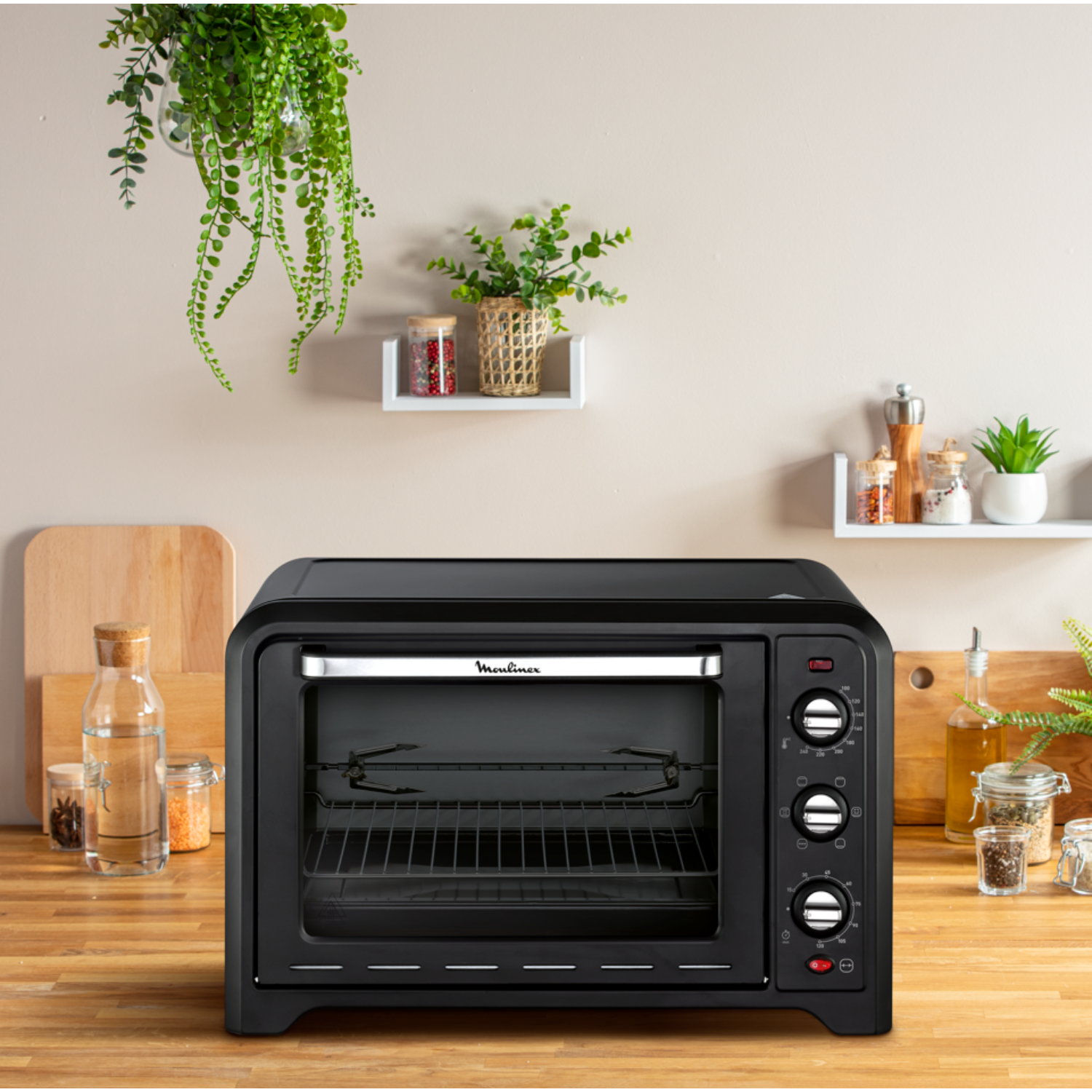 Black Moulinex oven on a wooden counter. Plants and other kitchen items in the background.