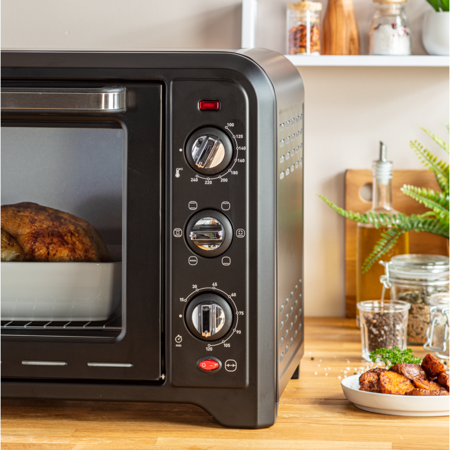 Black oven with food inside.  Knobs on the front. Wooden surface, white background.