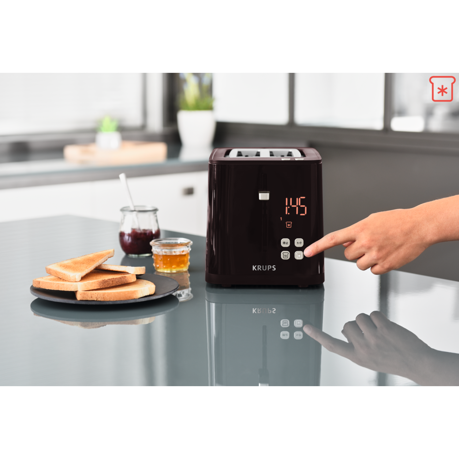 Grille-pain avec une main appuyant sur un bouton. Des toasts et de la confiture sont à proximité. L'affichage montre l'heure.