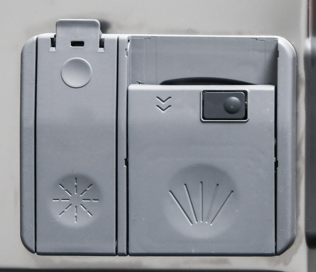 Dozownik do mydła do zmywarki. Widoczne są trzy przegródki, ze strzałkami i innymi znakami.