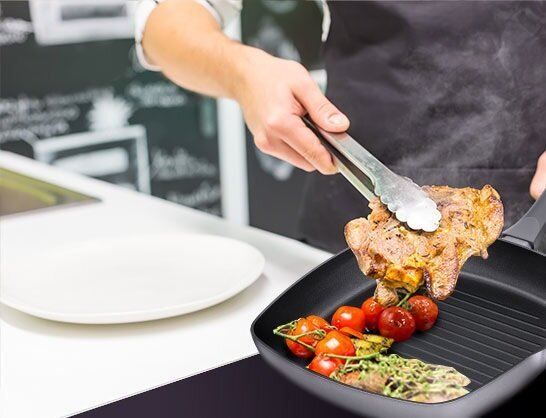 Osoba grilluje stek za pomocą szczypiec, z warzywami na patelni.