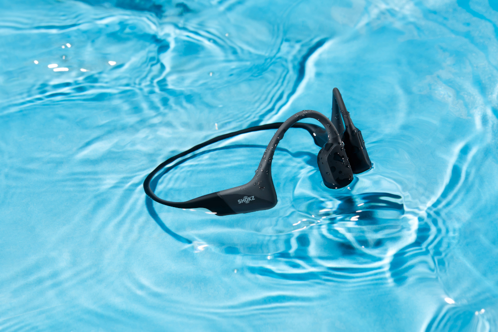 Casque Shokz noir immergé dans l'eau, montrant un fond d'eau bleu.