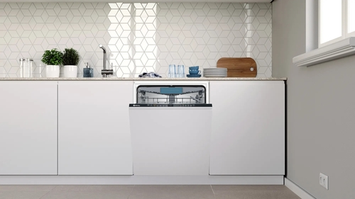 Lavavajillas en cocina blanca con encimera blanca y salpicadero hexagonal.