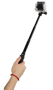 Osoba trzyma czarną kamerę GoPro na patyku do selfie. Kamera jest w wodoodpornej obudowie.