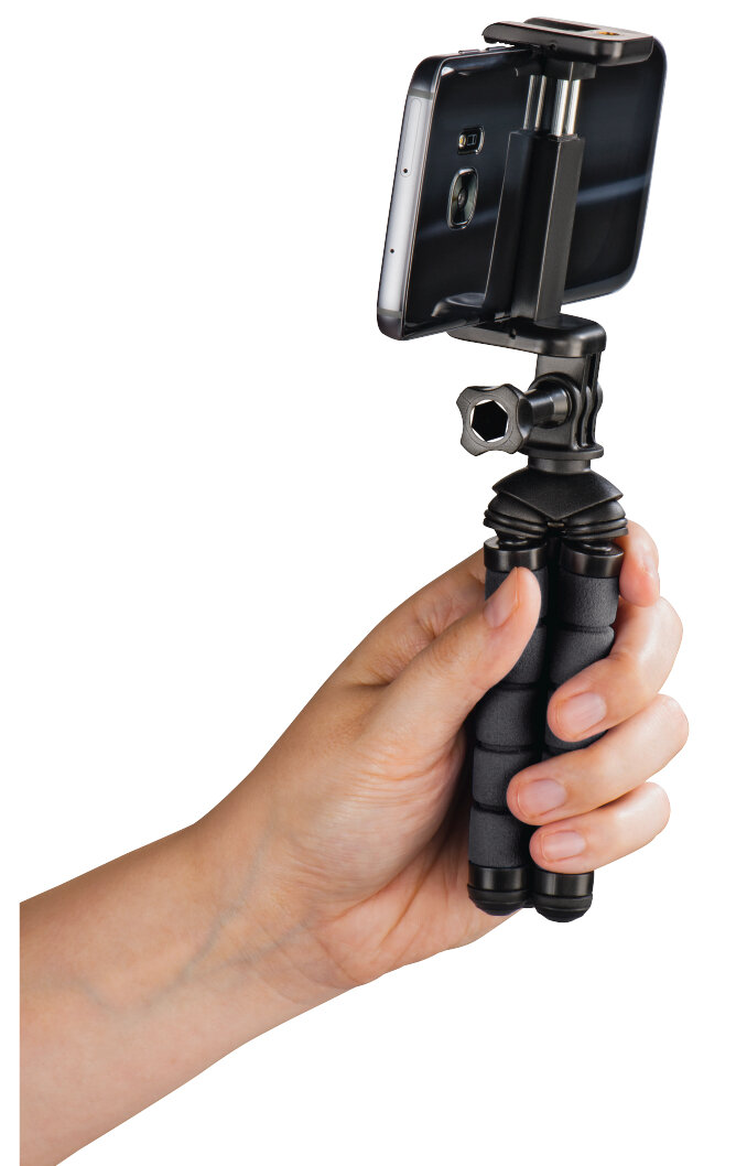 Dłoń trzymająca czarny statyw z dołączonym telefonem, białe tło.