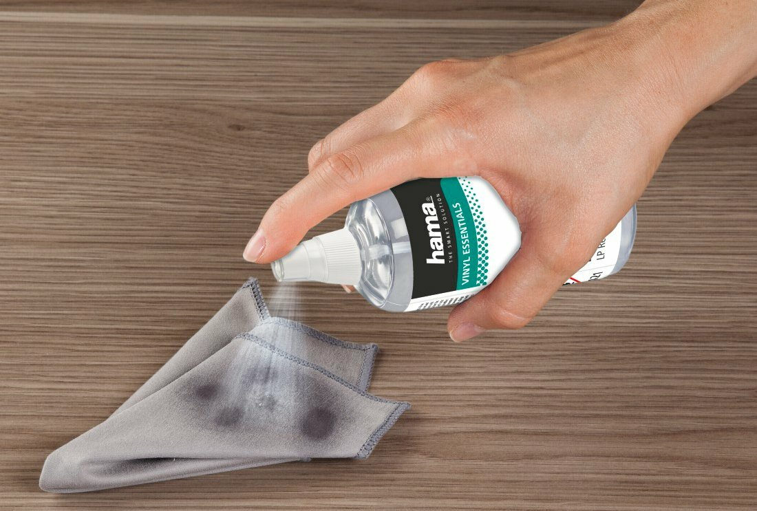 Ręka spryskuje roztwór czyszczący na szmatkę.