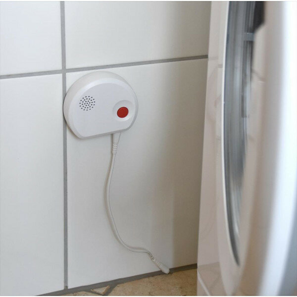 Białe urządzenie alarmowe z czerwonym przyciskiem na ścianie z kafelków.