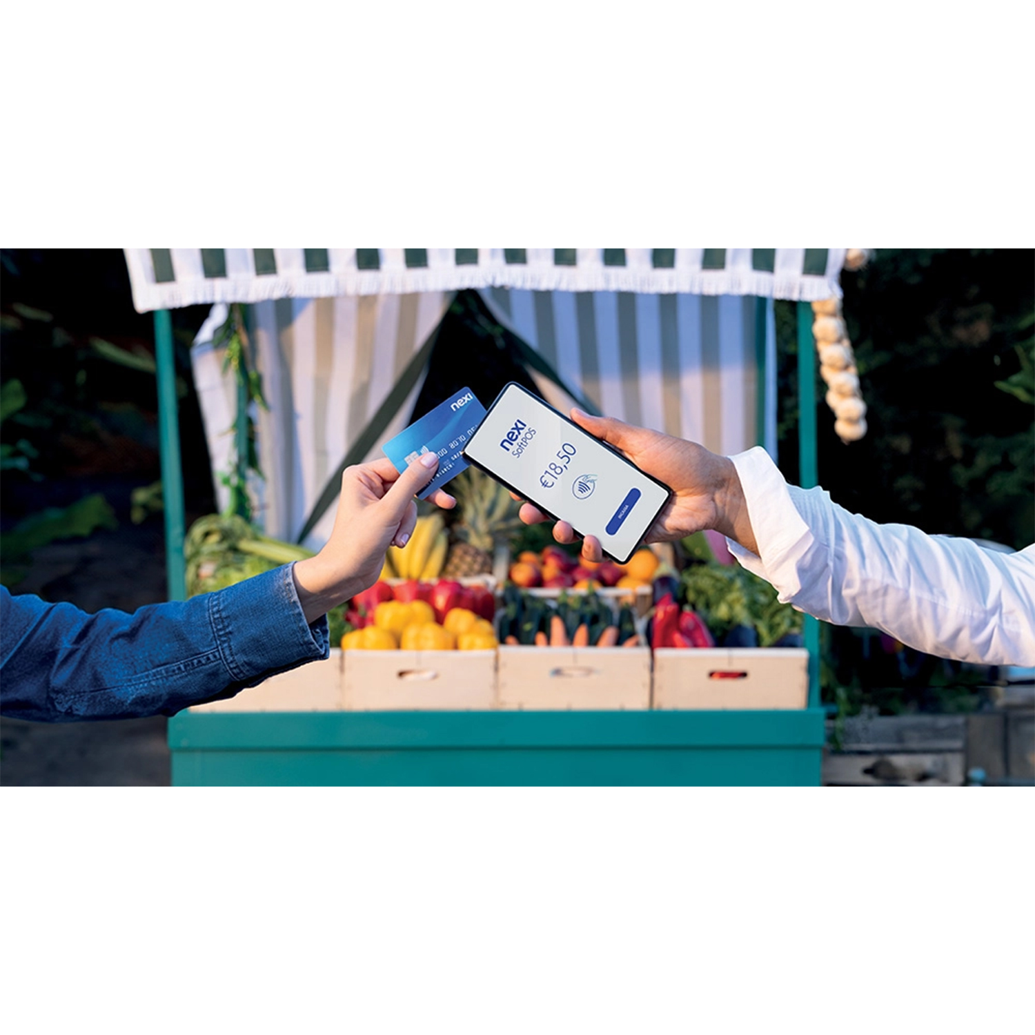 Persona paga con carta su telefono davanti al mercato. Importo: 18,50 €.