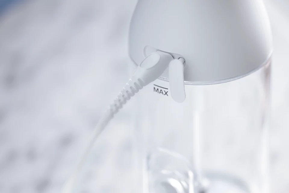 Un primo piano di un vaporizzatore da viaggio bianco con un cavo bianco e un indicatore di livello max.