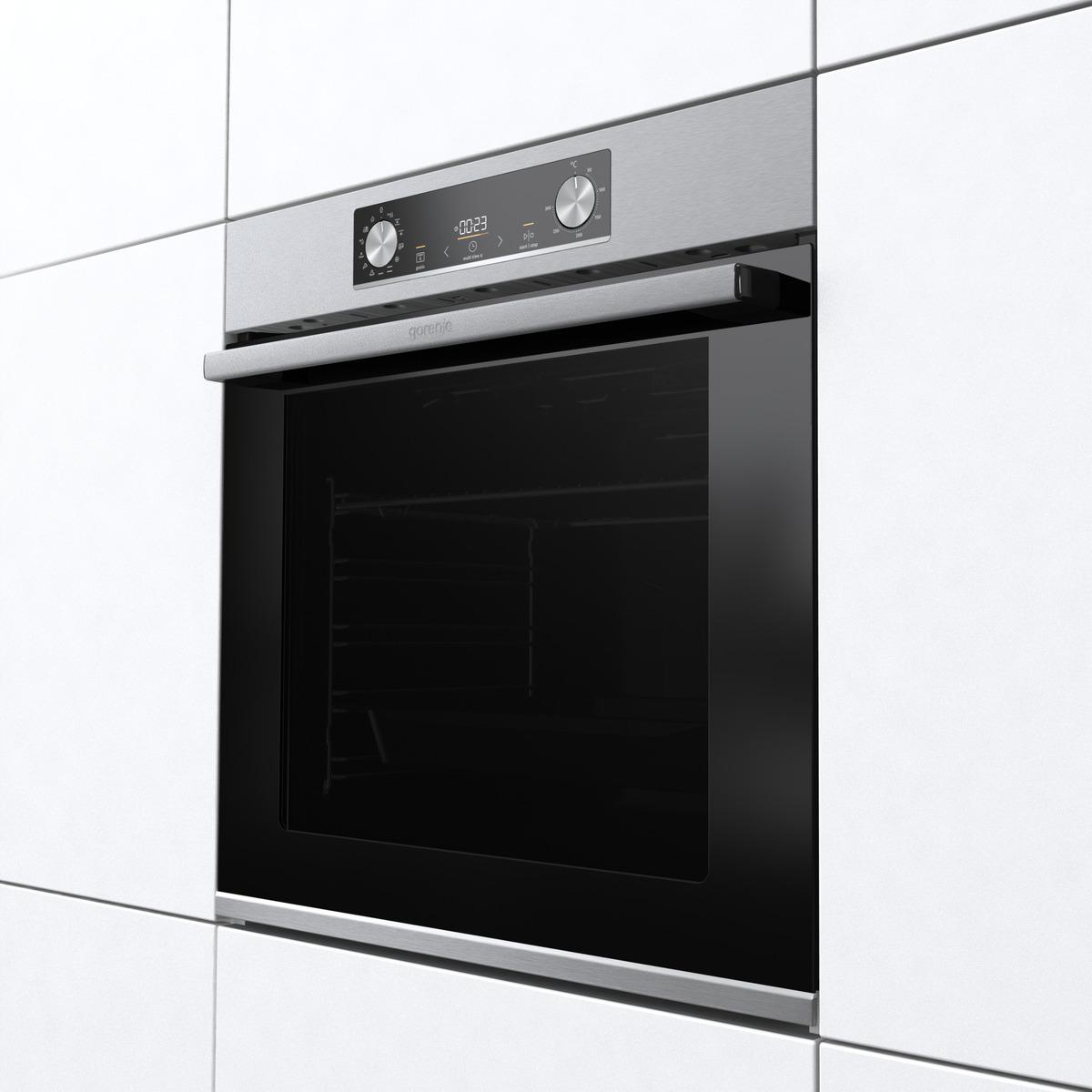Edelstahlofen in eine weiße Fliesenwand eingebaut. Schwarze Glastür.