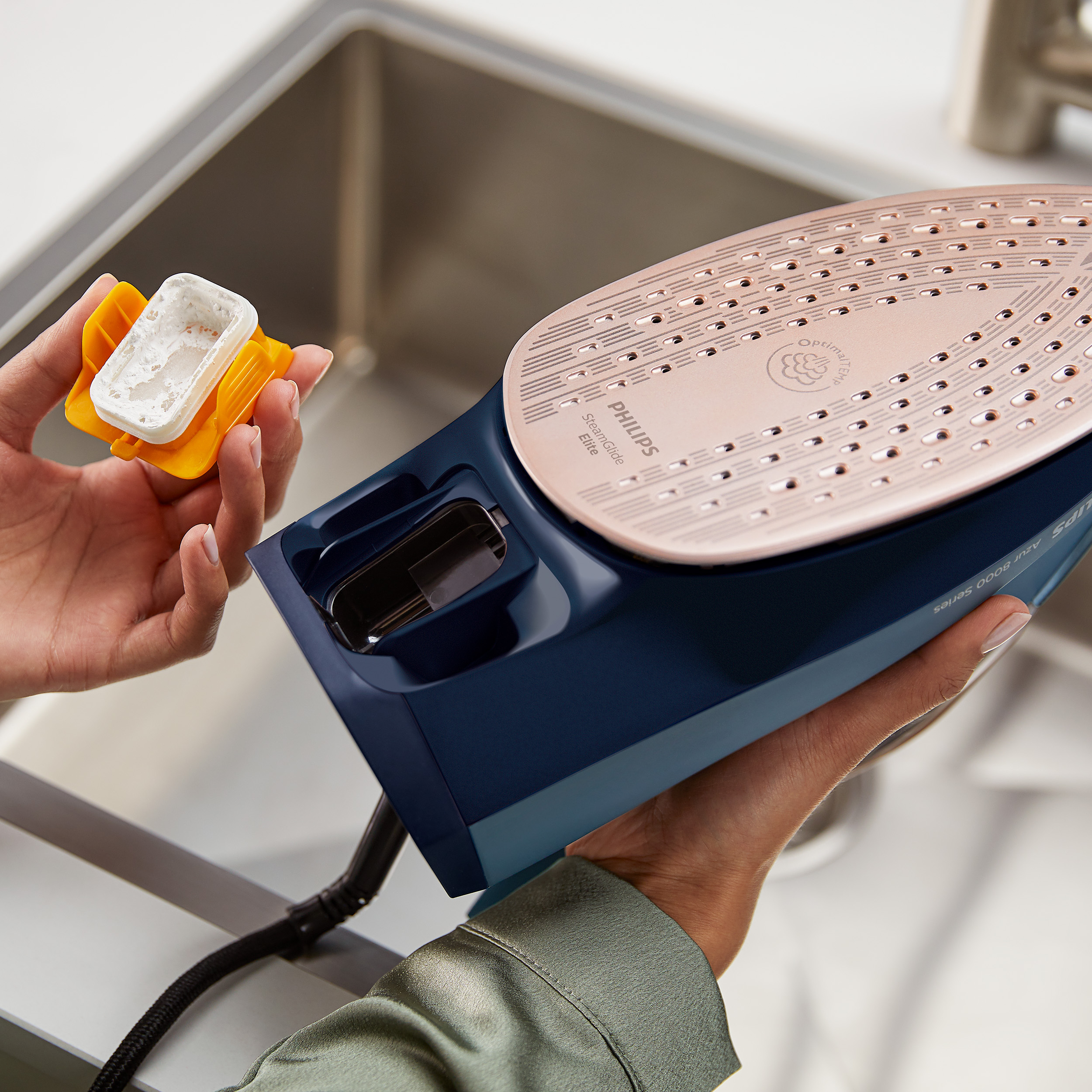 Hände entfernen einen Filter von einem Philips-Bügeleisen und zeigen die Basis des Bügeleisens.