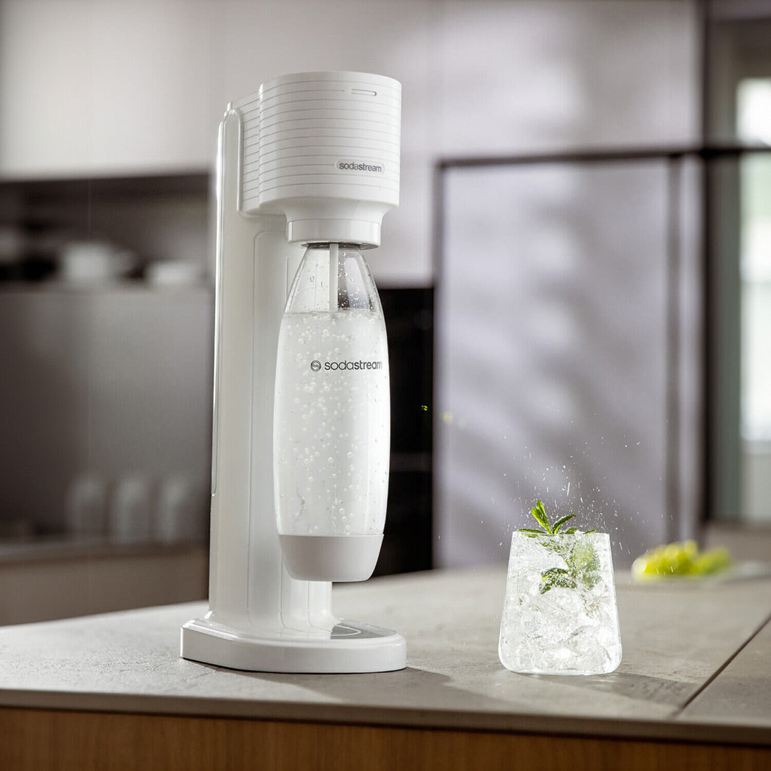 Fehér SodaStream gép egy pohár jéggel és mentával a konyhapulton.