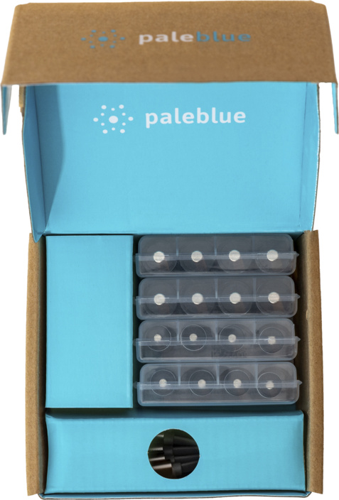 Scatola aperta con logo 'paleblue'. All'interno, una scatola azzurra contiene diversi contenitori trasparenti pieni di dischi neri.