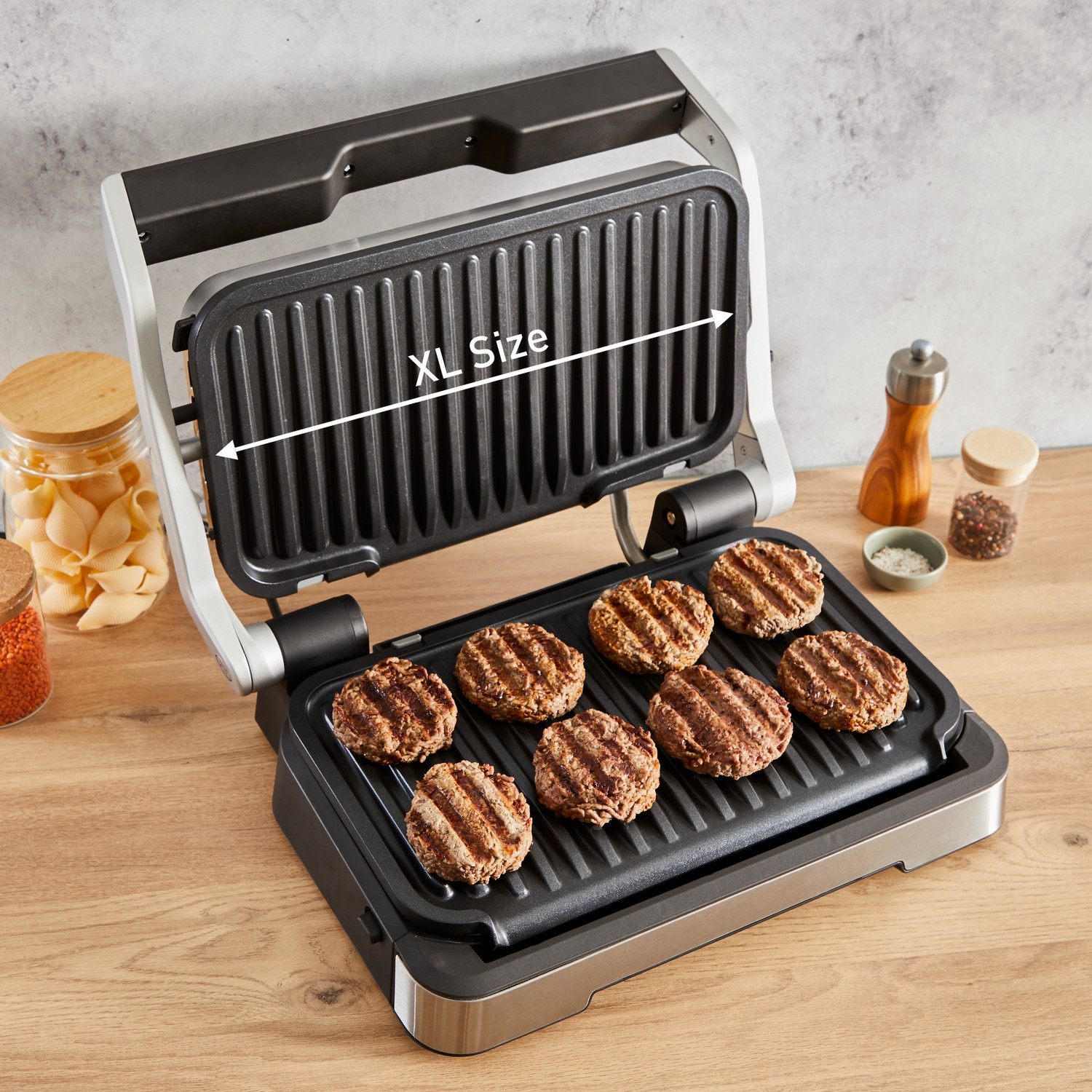 XL-grill met gebakken hamburgers. Houten tafelachtergrond met een pot en een zoutvaatje.