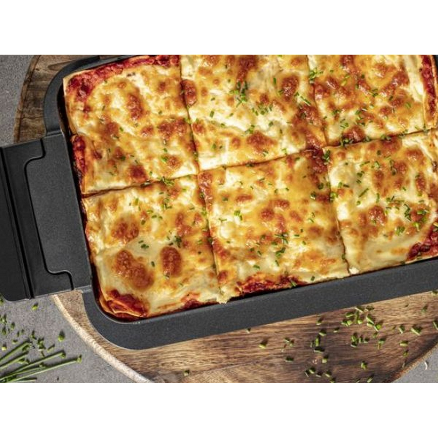 Lasagne in een zwarte bak op een houten oppervlak. Close-up.