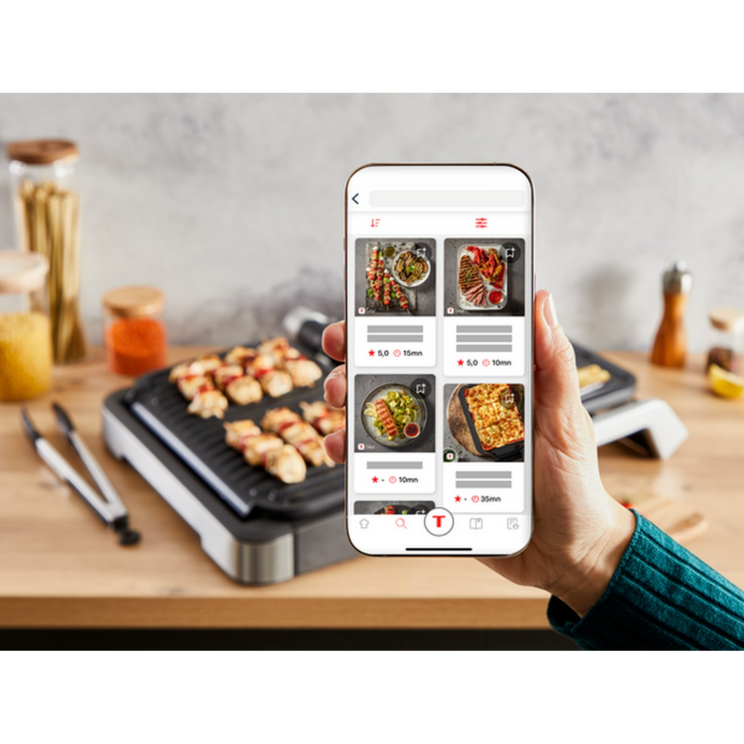 Een hand die een smartphone vasthoudt met een recepten-app met verschillende voedselfoto's.