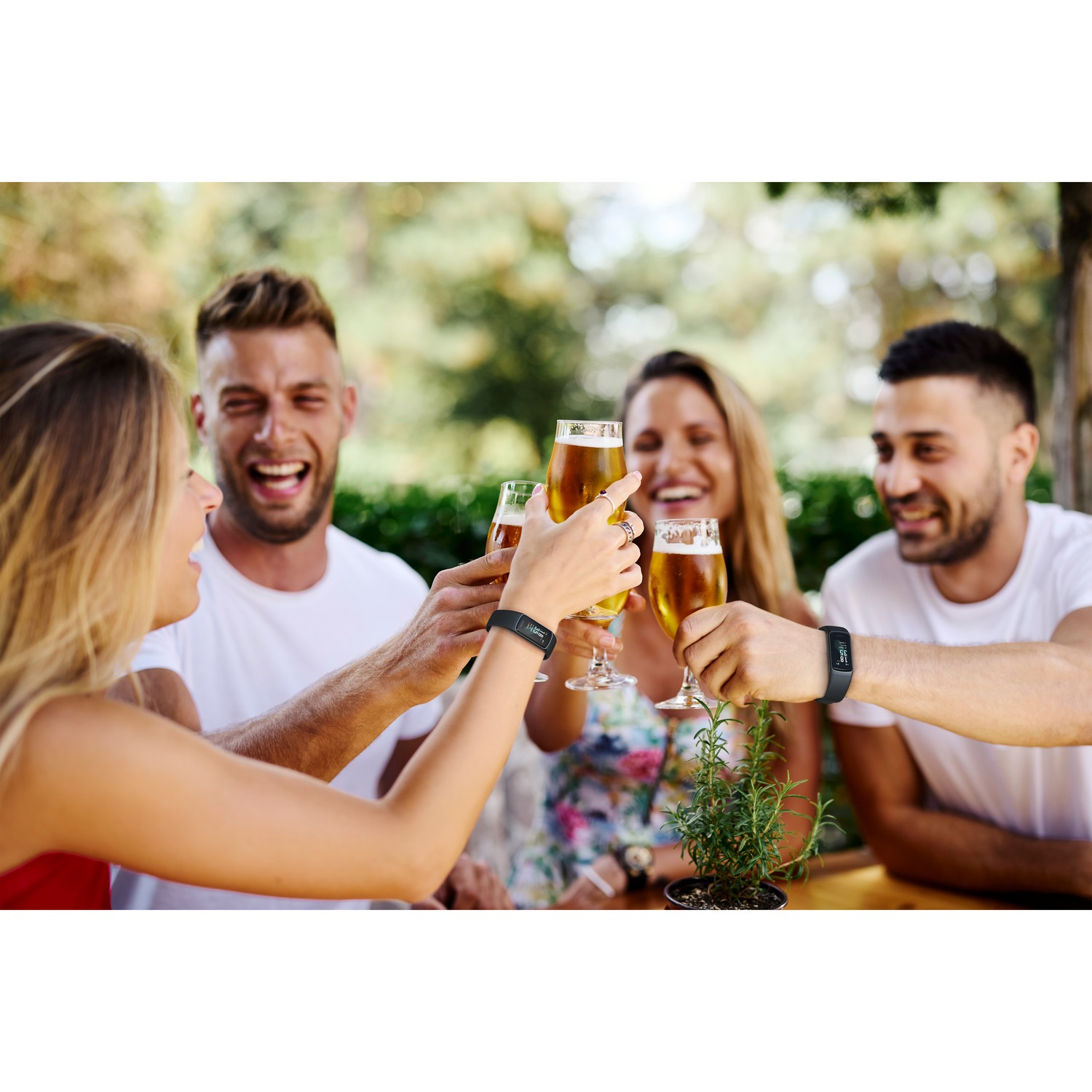Groupe d'amis trinquant avec des verres à bière en extérieur, portant des smartwatches.
