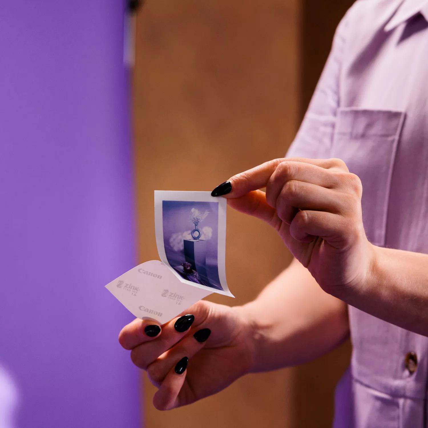 Hände halten ein Foto und ziehen einen Zink-Papierdruck ab.