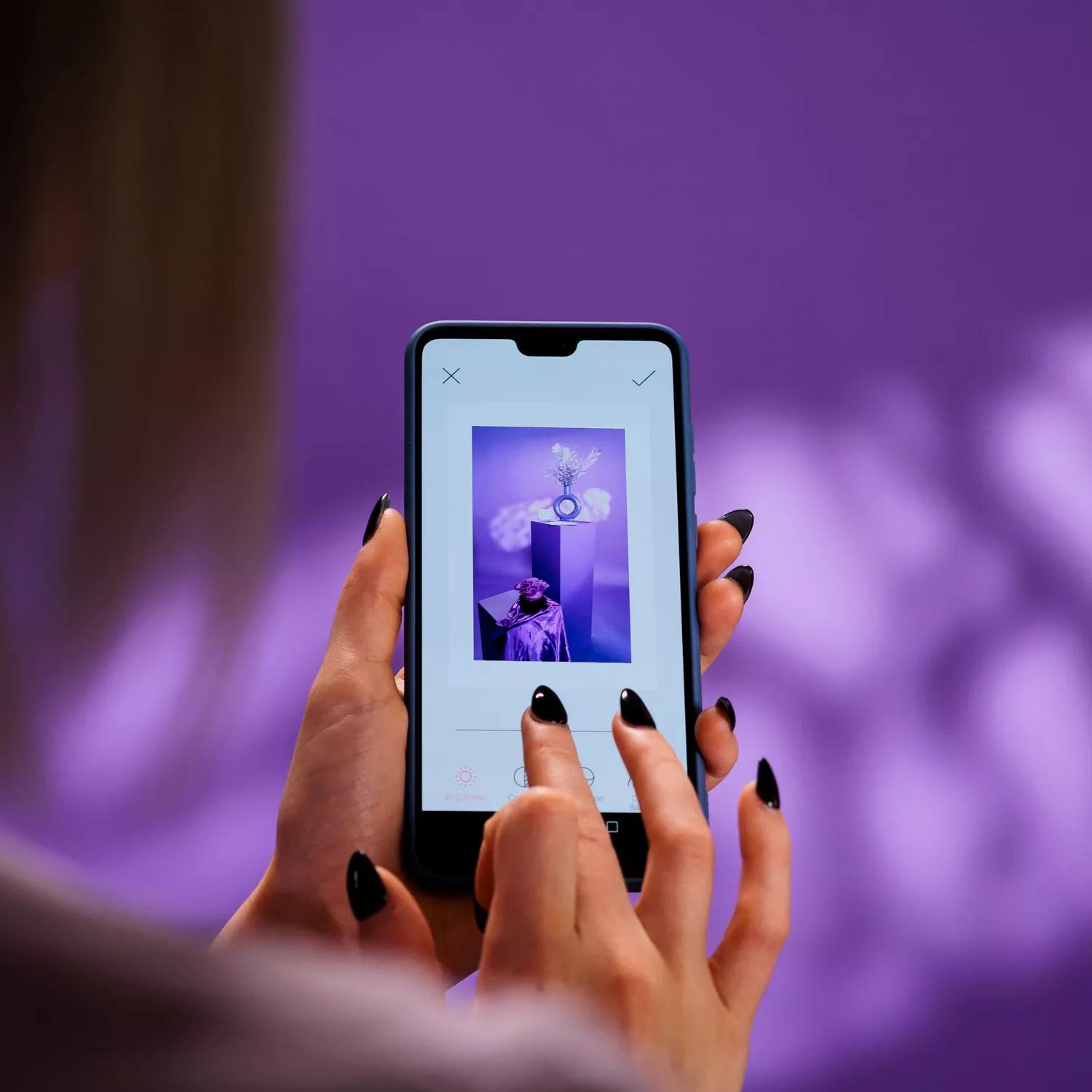 Person hält ein Telefon, das ein Bild mit lila Hintergrund anzeigt.
