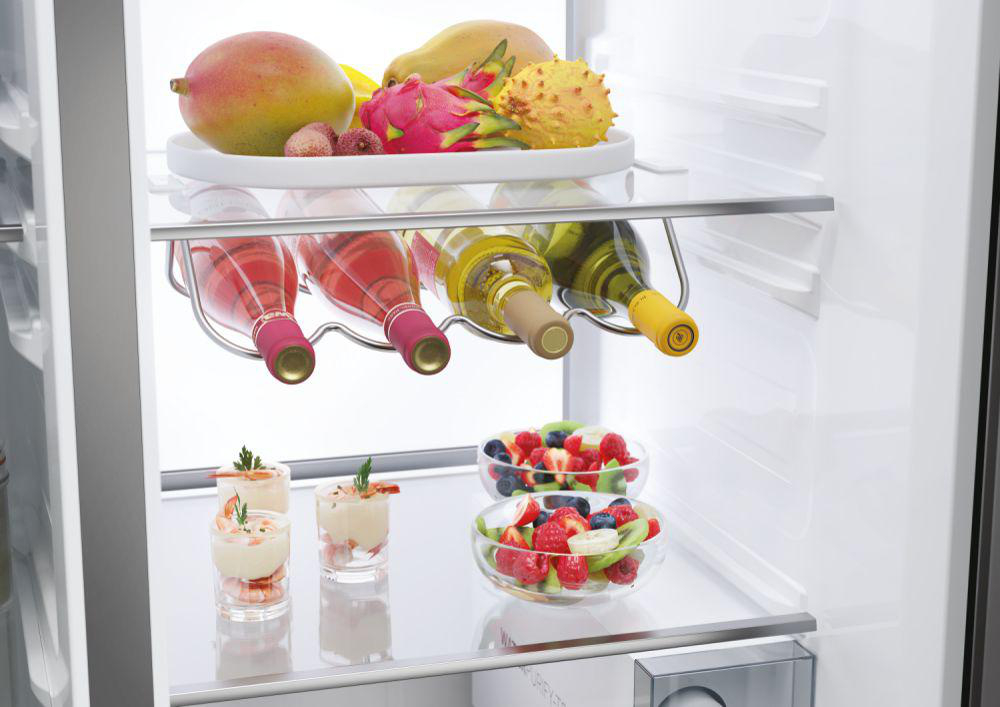 Obst, Wein und Vorspeisen im Kühlschrank auf den Regalen.