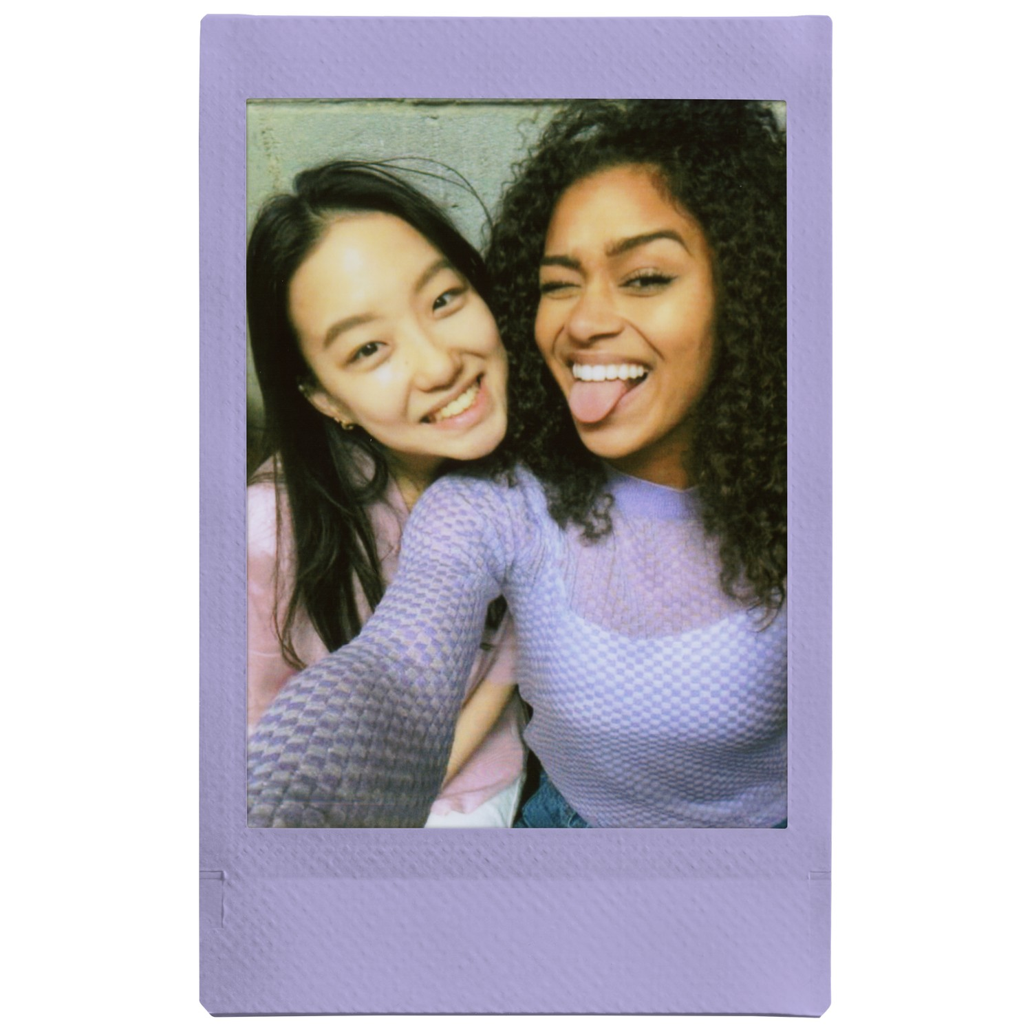 Deux femmes souriantes, une avec des cheveux foncés et une avec des cheveux bouclés, posant pour une photo polaroid.