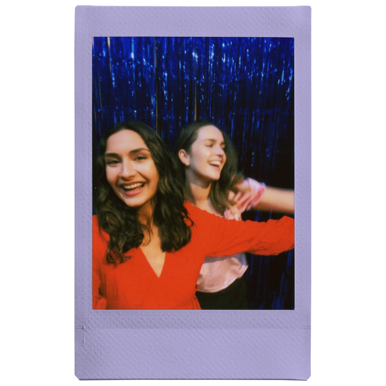 Deux femmes souriantes sur une photo polaroid. L'une porte du rouge, l'autre rose clair, sur fond bleu.