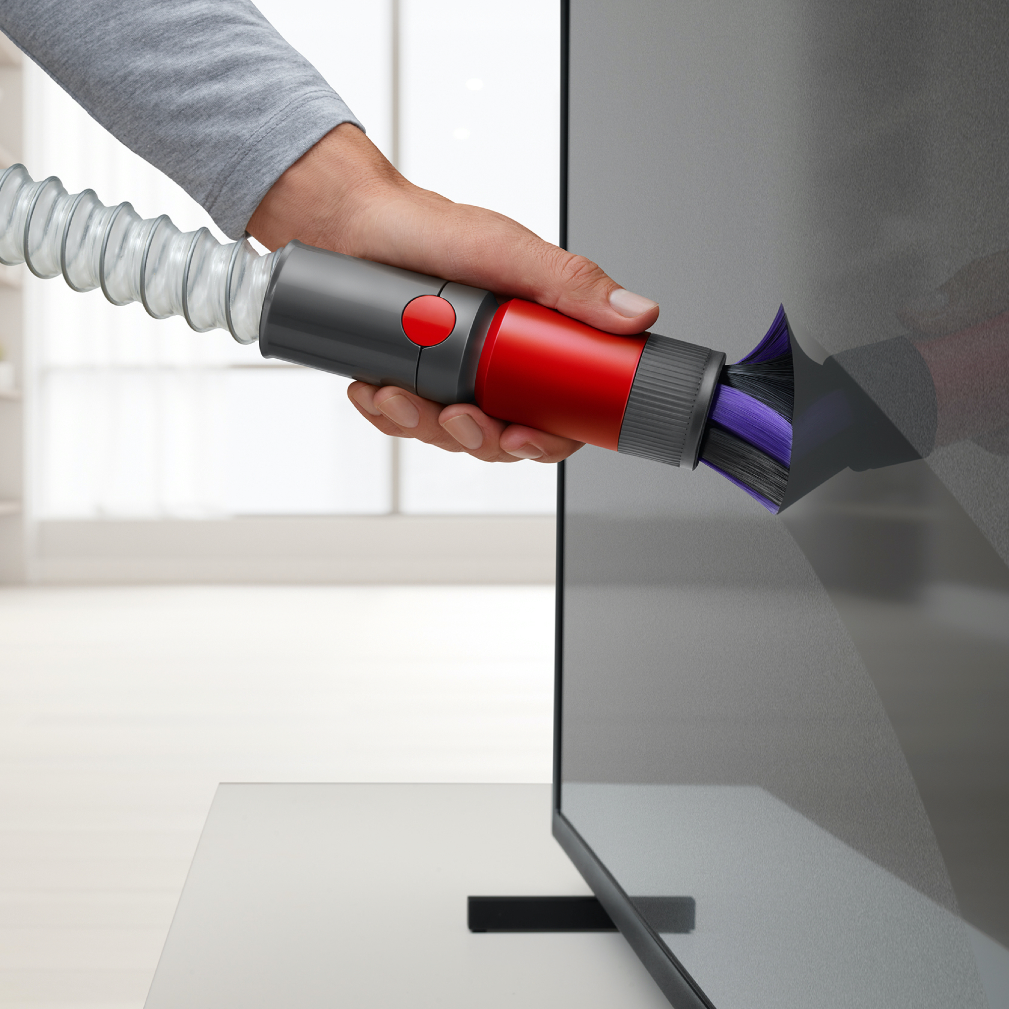 Hand benutzt Staubsauger, um TV-Bildschirm zu reinigen, TV ist schwarz.