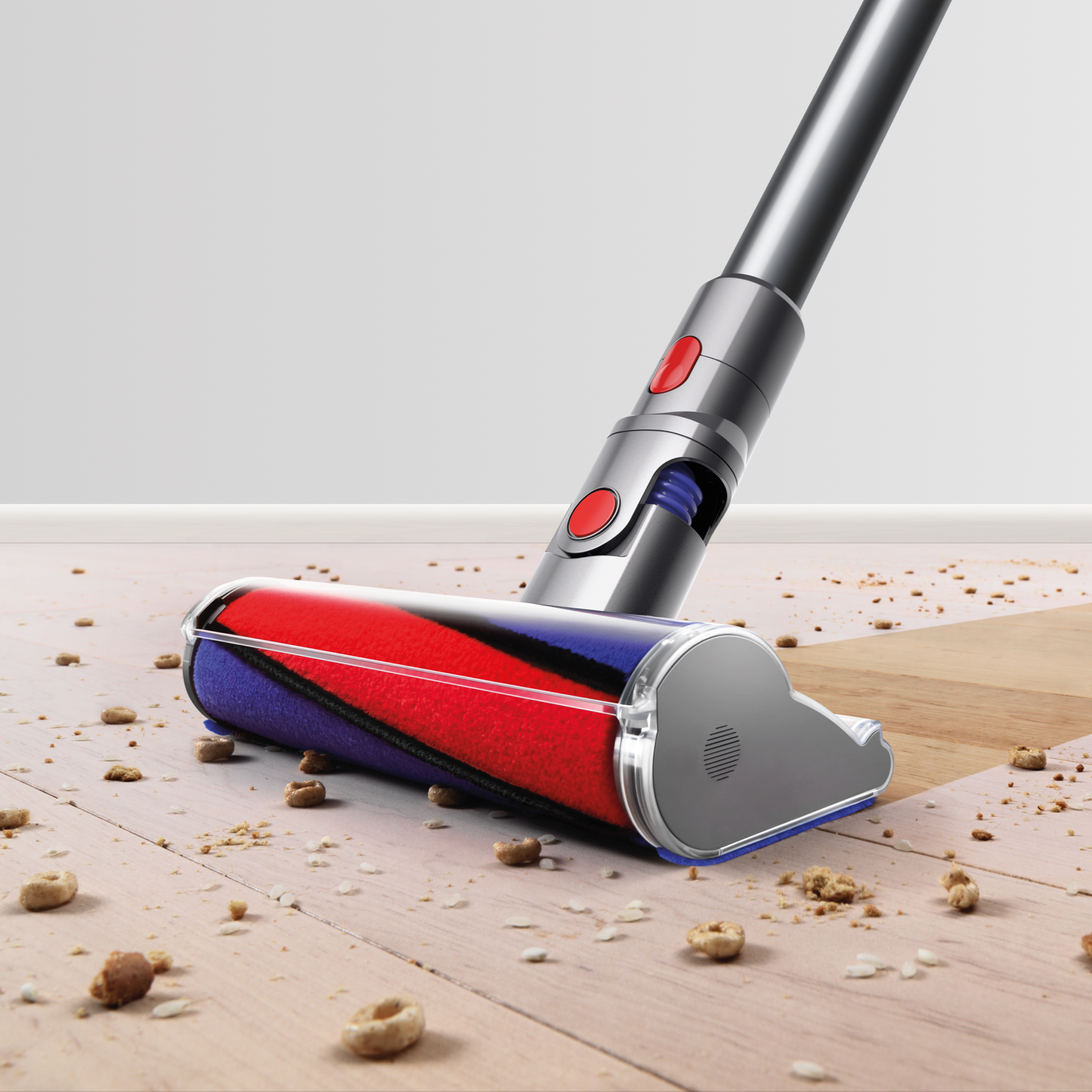 Dyson Staubsaugerkopf auf Holzboden, mit herumliegenden Ablagerungen.