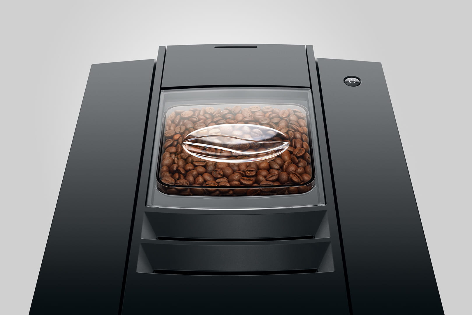 Vista superior de una cafetera con granos de café en un recipiente transparente.