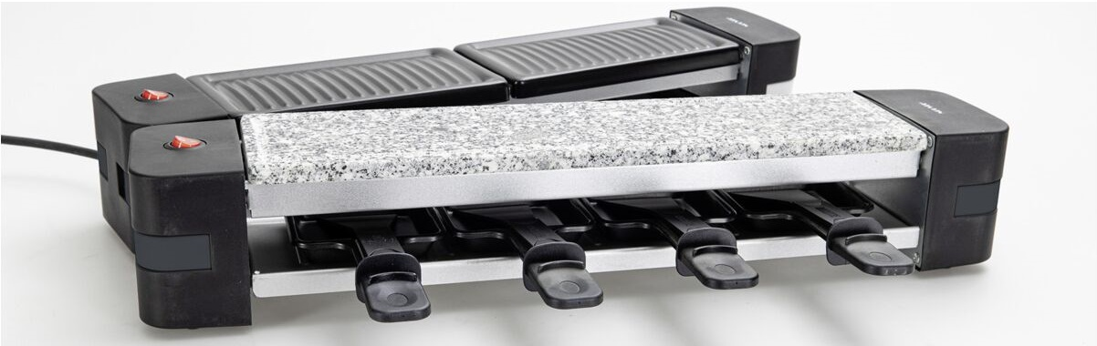 Una griglia per raclette con quattro vassoi per formaggio, pietra per grigliare.